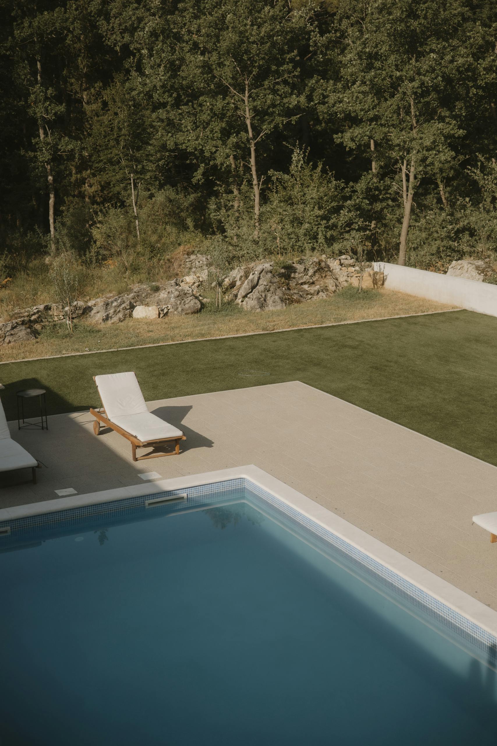 Peaceful outdoor pool area with sun loungers overlooking greenery in Omiš, Croatia.